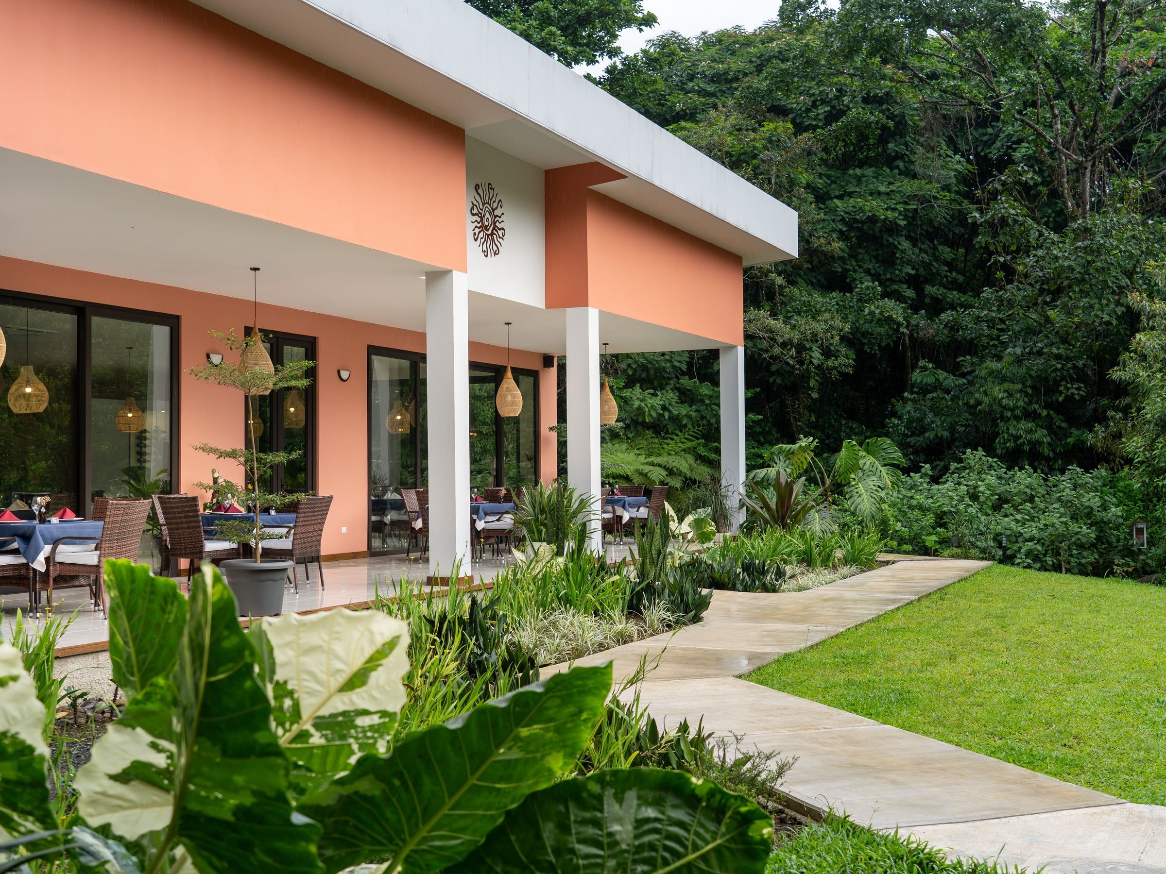 Terraza abierta de Yan's Bistro entre jardines tropicales, restaurante de cocina fusión en Horquetas de Sarapiquí sobre la Ruta 4, a 3 km del Cruce de Río Frío